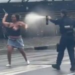 巨大なナイフで警察に襲い掛かる黒人女、スプレーを噴射される